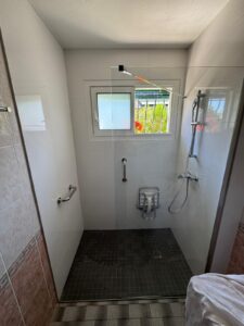 Douche de plain-pied adaptée avec barres d'appui et siège rabattable