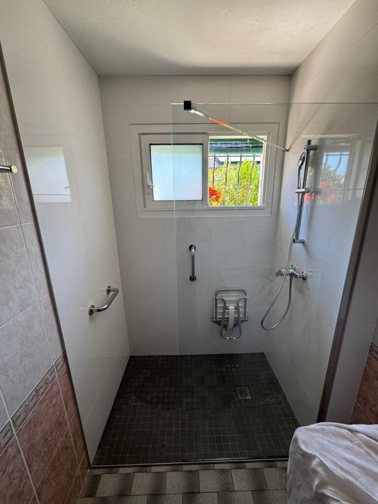 Douche de plain-pied adaptée avec barres d'appui et siège rabattable